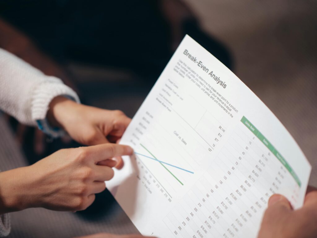pexels photo 6774148 6774148 Close-up of hands discussing a break-even analysis document in a business meeting.